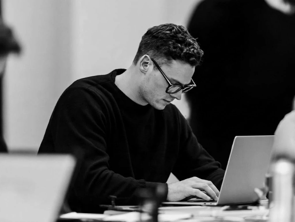 A team member working at a laptop in a busy office